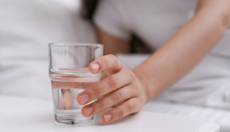 Een hand reikt naar een glas water