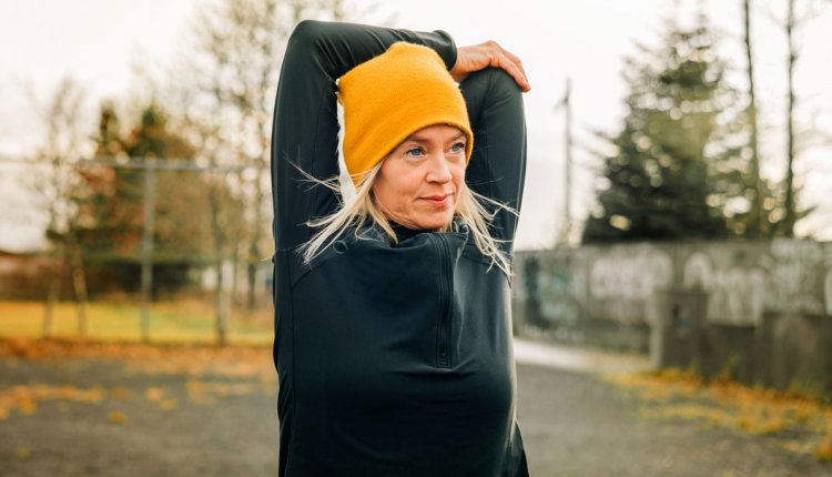 Vrouw rekt en strekt in de ochtend voor het sporten buiten in de kou