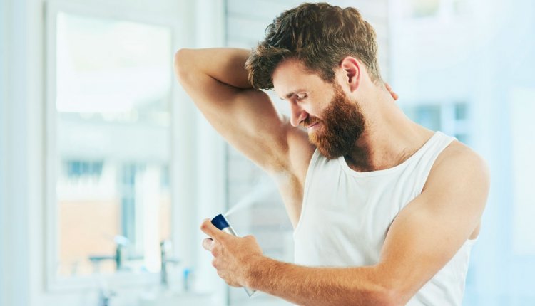 Man spuit deodorant onder zijn arm