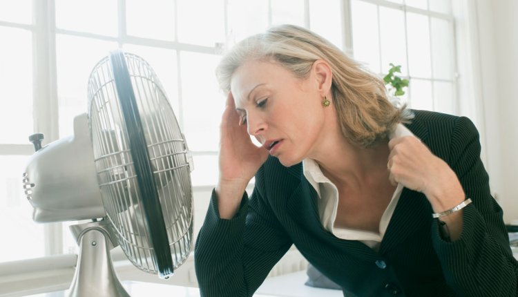 Vrouw heeft het warm en zit voor ventilater om af te koelen