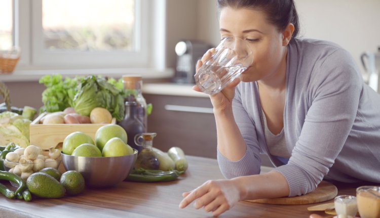 Vrouw doet aan bulkdrinken in de keuken met glas water