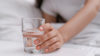 Een hand reikt naar een glas water