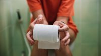 Vrouw op toilet met toiletpapier in de handen